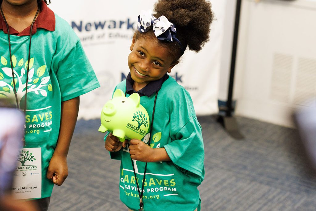 A rising kindergartner holds her Newark Saves piggy bank. She is one of thousands of kindergartners the district will enroll in a college savings plan this year.